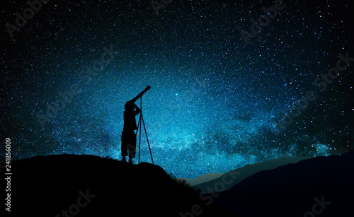 Silhouette of little child looking through a telescope
