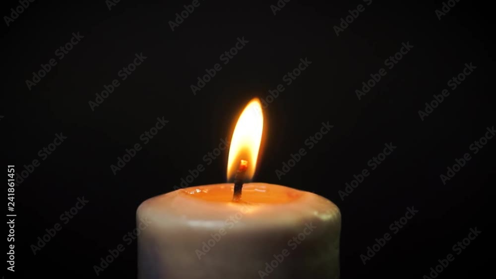 white candle burns in the dark on a black background with dripping wax white candle burns in the dark on a black background with dripping wax