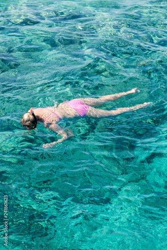 Young girl snorkeling in tropical water on vacation. Woman swimming in blue sea. Snorkeling girl in full-face snorkeling mask. vertical photo.
