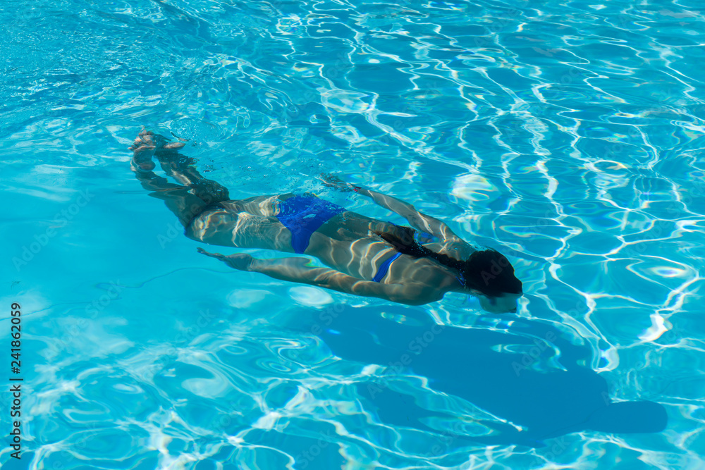 Woman with swimsuit swimming on a blue water pool. Underwater woman portrait with blue bikini in swimming pool.