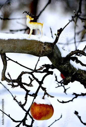 appple and deer figurine on a snow covered apple branch photo