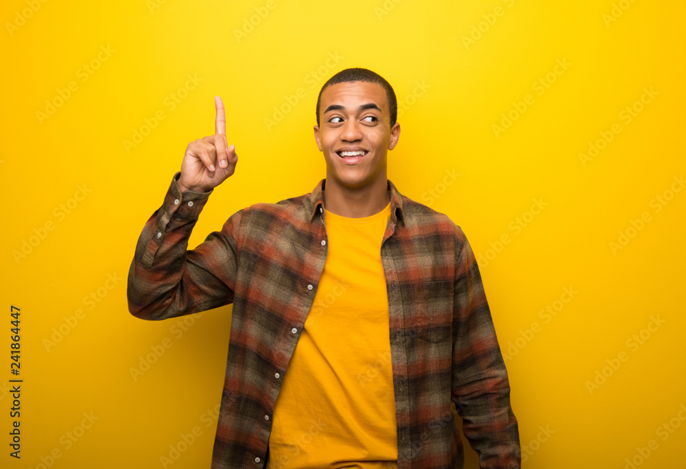 Young african american man on vibrant yellow background intending to realizes the solution while lifting a finger up Young african american man on vibrant yellow background intending to realizes the solution while lifting a finger up