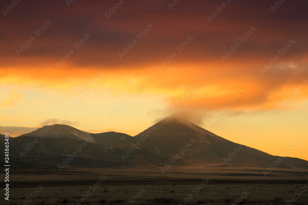 Fiery orange clouds swirl around mountains in Dugway Valley, Utah at sunset. Fiery orange clouds swirl around mountains in Dugway Valley, Utah at sunset.