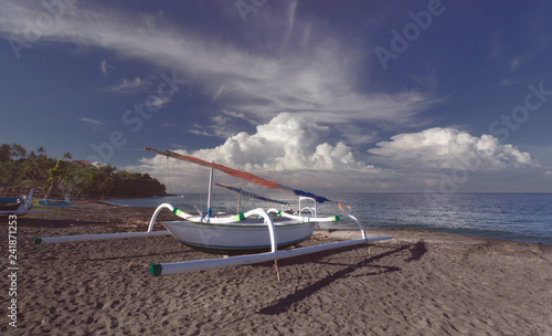 Catamaran on a sandy seashore with sun and clouds