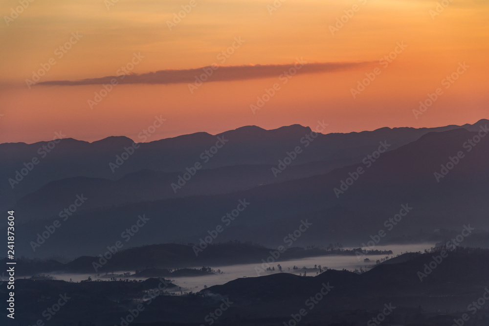 Sunrise view over mountain from a mountain peak. Panorama view over mountains and lake. Misty morning just after sunrise. Nature landscape.