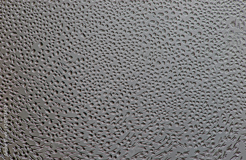 Winter motif on glass of frozen drops. A lovely background of frozen drops of water on the glass. Window glass with cold foggy condensation abstract closeup background 