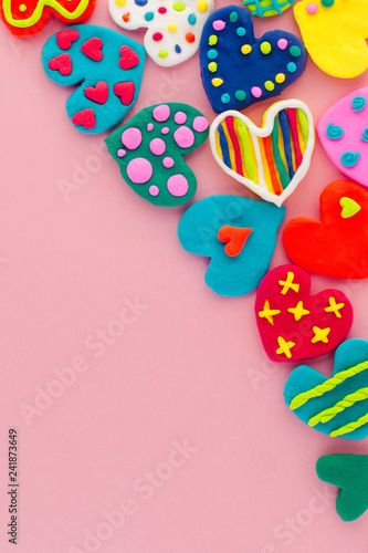 Colorful handmade plasticine hearts on pink background with copy space