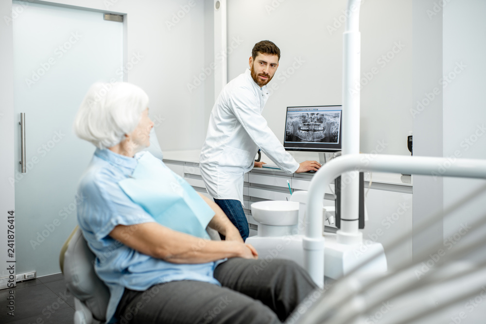 Dentist showing panoramic shot of the jaw on the computer to the elder woman during the consultation in the dental office Dentist showing panoramic shot of the jaw on the computer to the elder woman during the consultation in the dental office