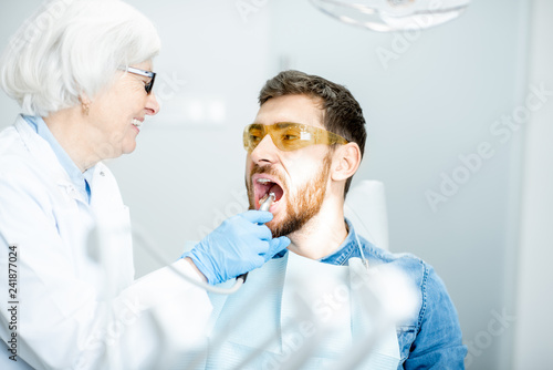 Photography Handsome man during the medical examination with elderly woman dentist in the de