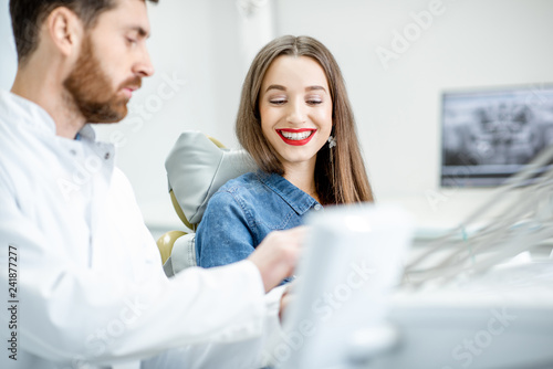 Young beautiful woman during the medical consultation with male dentist in the dental office