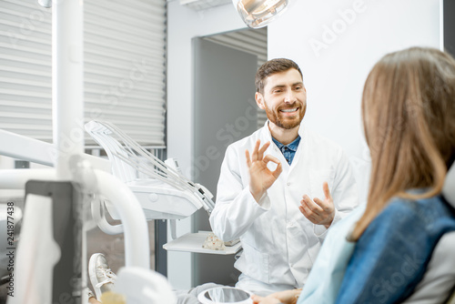 Handsome dentist talking with woman patient during the medical consultation in the dental office