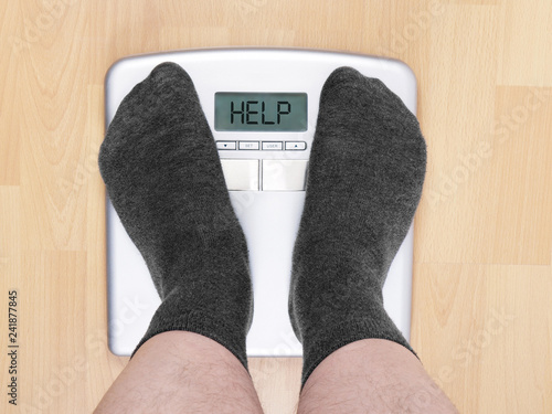 Foto overweight man on personal scales, display reads help