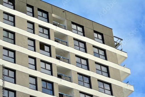 New block of modern apartments with balconies and blue sky in the background