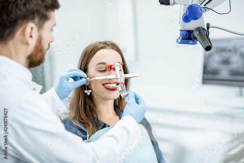 Dentist putting jaw measurement system to a young woman patient in the dental office