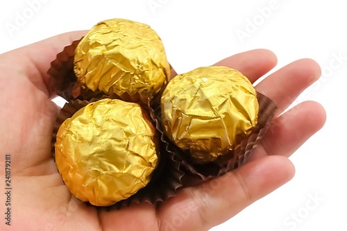 Fotografie Hand Holding Round Chocolate Candies in Gold Package