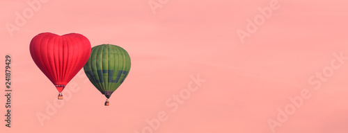 Fototapeta Naklejka Na Ścianę i Meble -  Red heart shaped and green air ballons isolated in the sky, trendy color coral toned banner