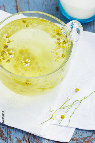 Fresh chamomile blossom tea in a glass cup on a wooden table, healthcare and healthy eating concept
