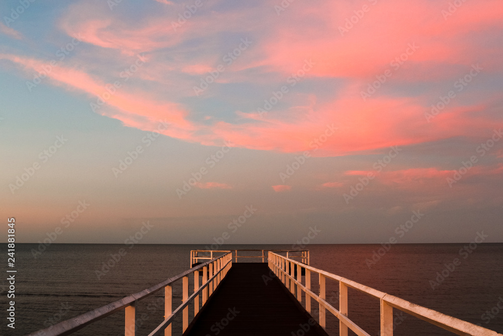 Obraz premium Wooden pier during sunset overseeing the ocean with pink horizon and turquoise sky (Hervey Bay near Fraser Island, Queensland, Australia)