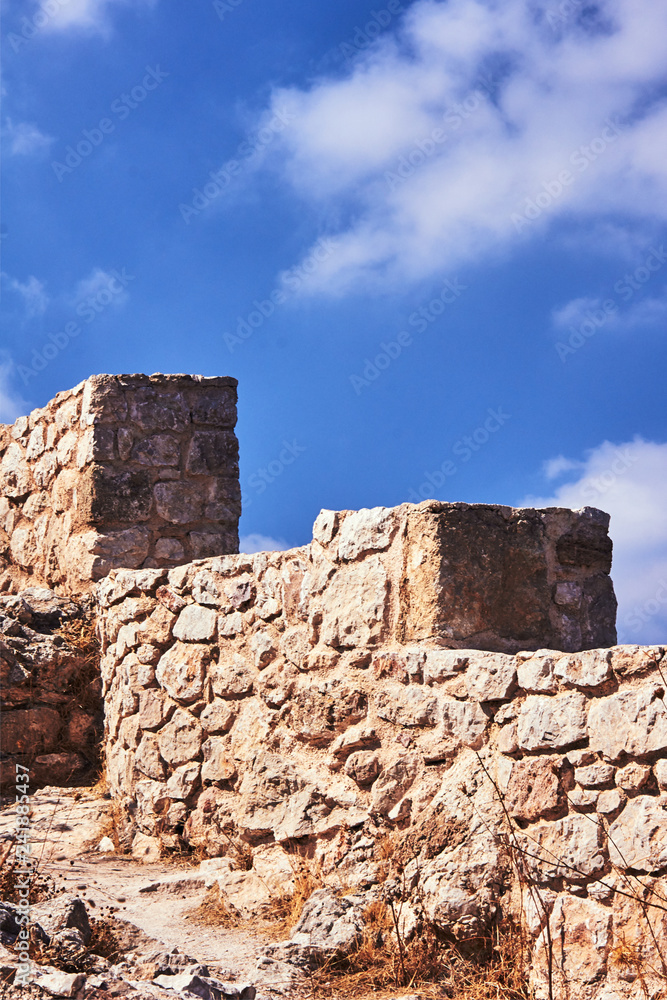 Crash stone ramparts against the white clouds and blue sky on the island of Rhodes.