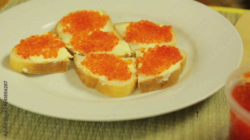 A jar of red caviar and a white plate with canapes with butter and cavia A jar of red caviar and a white plate with canapes with butter and cavia