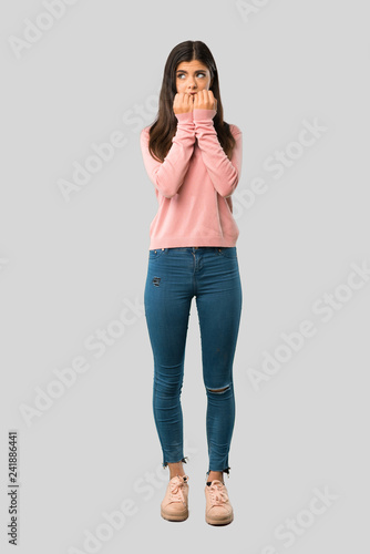 Full body of Teenager girl with pink shirt is a little bit nervous and scared putting hands to mouth on isolated grey background photo