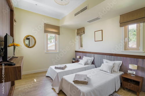 Interior of a spacious light bedroom with windows in a luxury villa. Big comfortable double bed in elegant modern bedroom