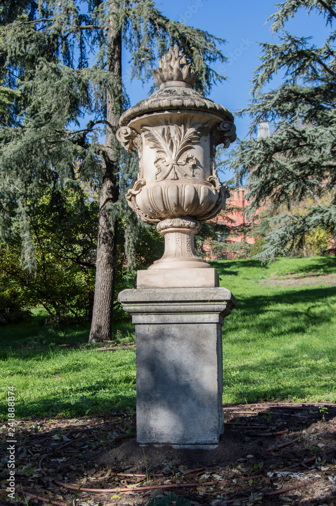 Copa de piedra/ Una copa de piedra  con pedestal decorando un jardín en Madrid. España.