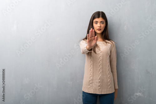 Teenager girl with sweater on a vintage wall making stop gesture denying a situation that thinks wrong © luismolinero