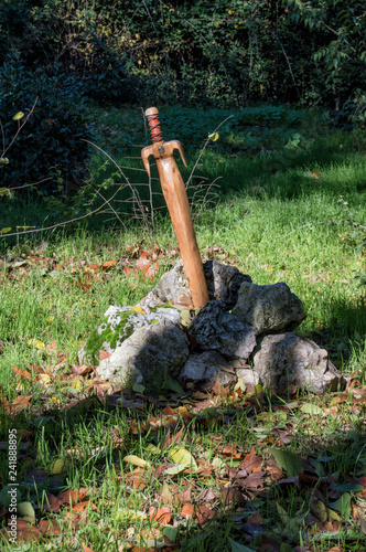 Espada de Excalibur/ una espada de madera clavada en una piedra decorando un jardín en Madrid. España. photo