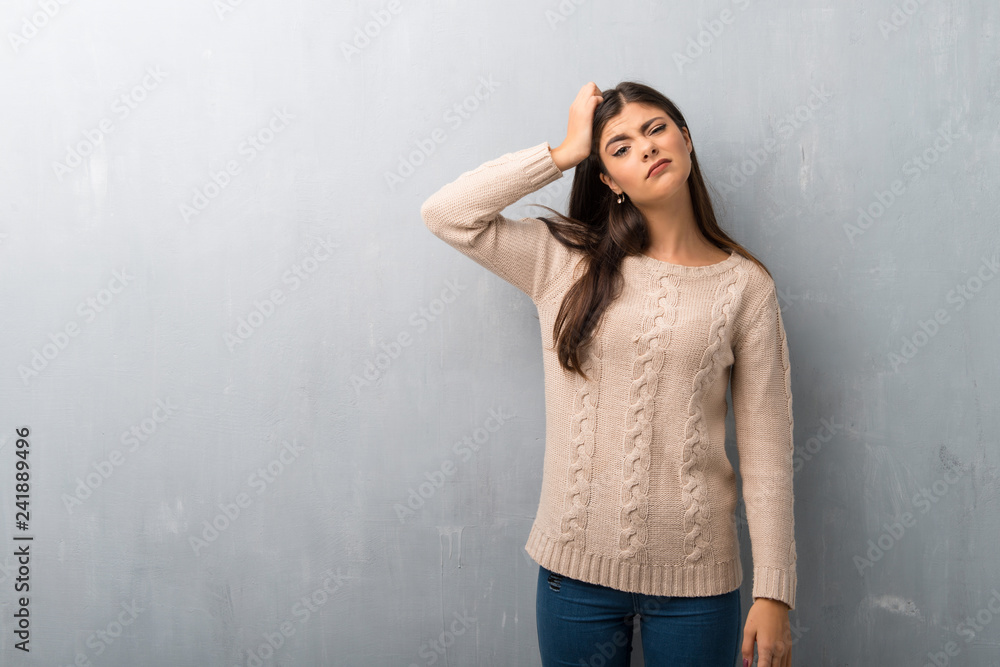 Teenager girl with sweater on a vintage wall with an expression of frustration and not understanding