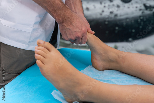 Osteopath therapist makes manipulation and massage to foot the patient.