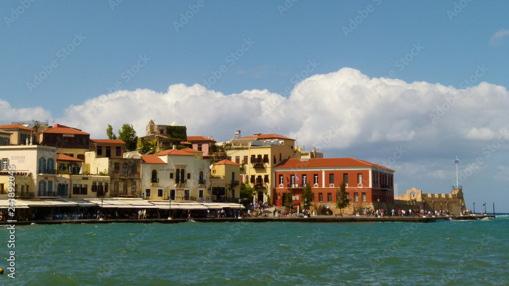 View of the embankment of Chania with a turquoise sea and blue sky with a white cloud