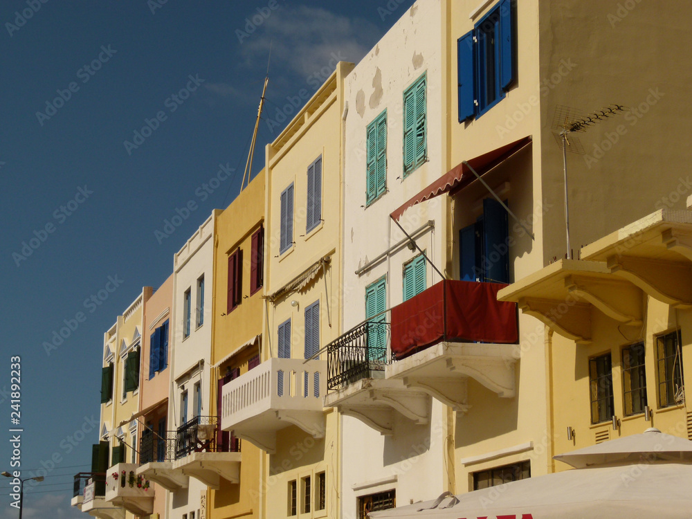 Chania houses with colored shutters and balconies under a blue sky, Crete