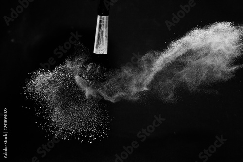 Cosmetic brush with white cosmetic powder spreading for makeup artist or graphic design in black background