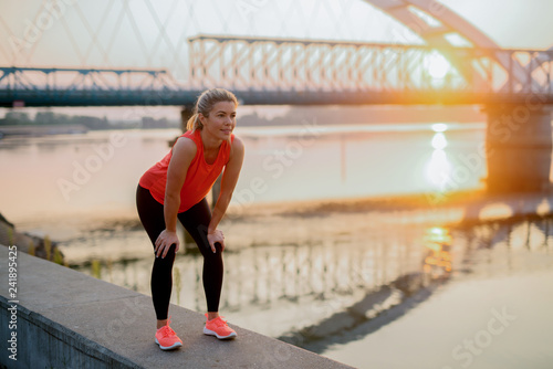 Fit young girl taking a few minutes to rest after hard outside training. Standing on river band.