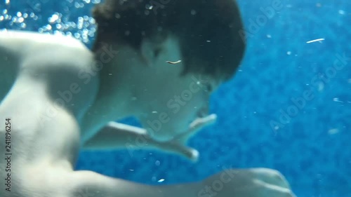 Child boy diving inside swimming pool during summer vacations