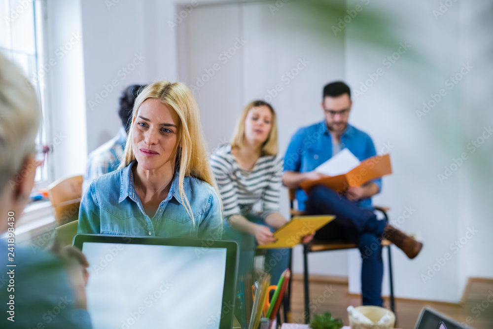 Fototapeta premium View of young cute girl on a job interview. Group of people sitting behind sitting and waiting for their turn.