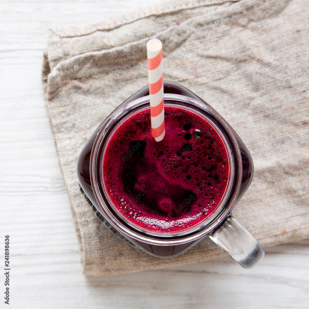 Glass jar of beetroot smoothie, view from above. White wooden background. Top view, overhead, flat lay. Closeup.