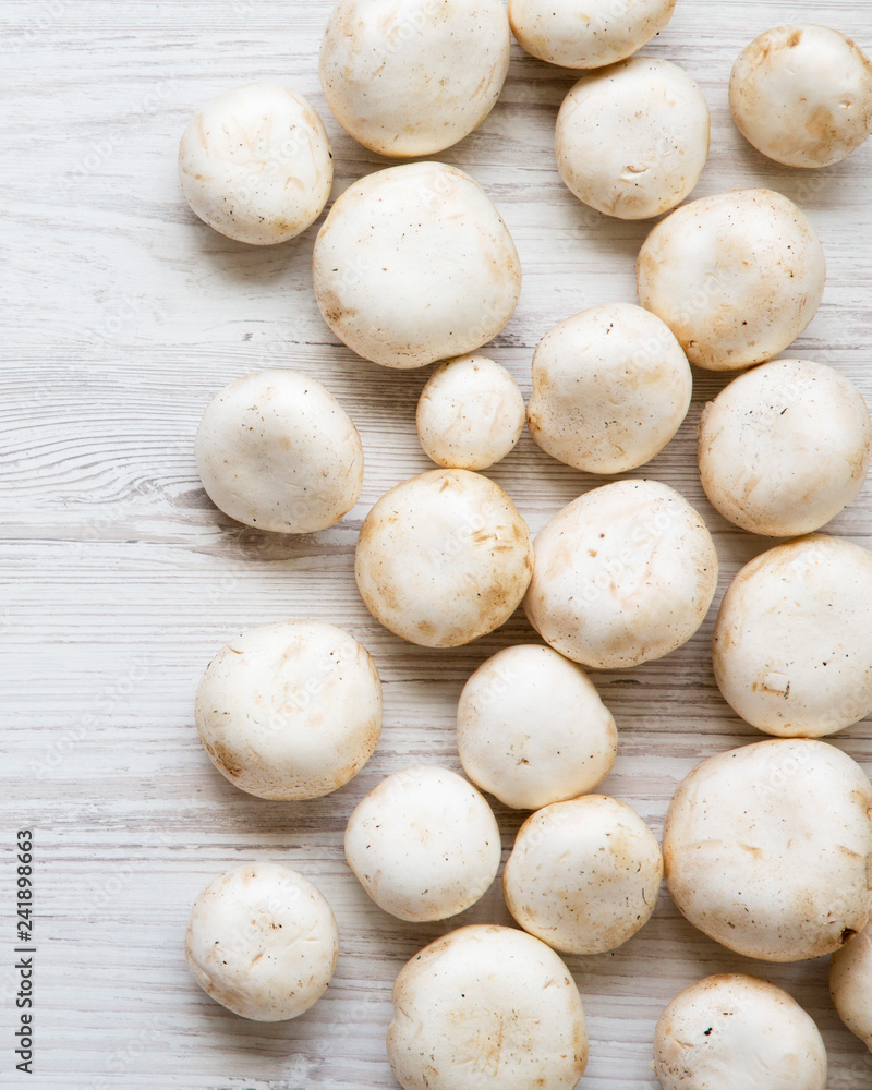 Champignon mushrooms on a white wooden surface, top view. From above. Closeup. Champignon mushrooms on a white wooden surface, top view. From above. Closeup.