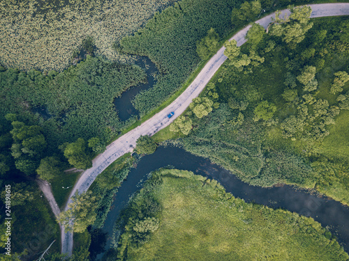 Aerial Photo of Car Driving on the Road going by the River under the Trees, Top Down View in Early Spring on Sunny Day
