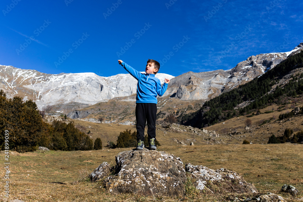 Fototapeta premium Little mountaineer on the peak of the mountains