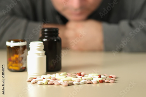 Depressed man beside a lot of pills, suicide concept