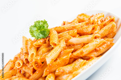 Penne with pesto decorated with parsley on a plate on a white background