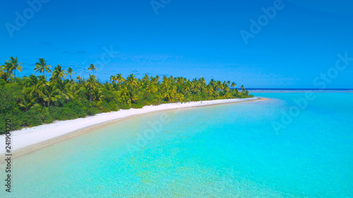 AERIAL: Flying over the tranquil shallow ocean water by the sandy shoreline.