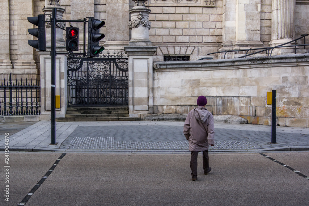 Close up back view of man crossing street. Red light on semaphore, danger. London, United Kingdom.