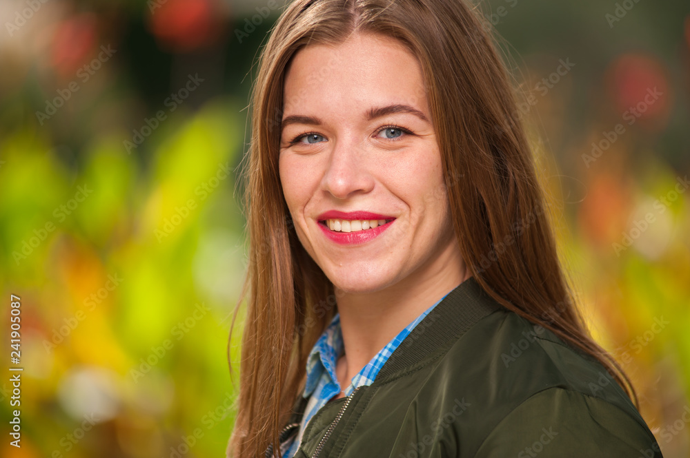 Close-up portrait of a smiling positive beautiful young woman looking into the camera on a sunny summer warm day outdoors Close-up portrait of a smiling positive beautiful young woman looking into the camera on a sunny summer warm day outdoors