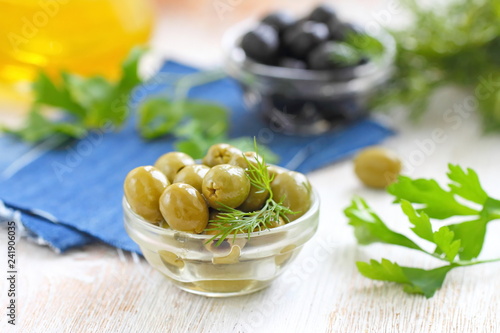 Green and black olives in glass bowls and olive oil