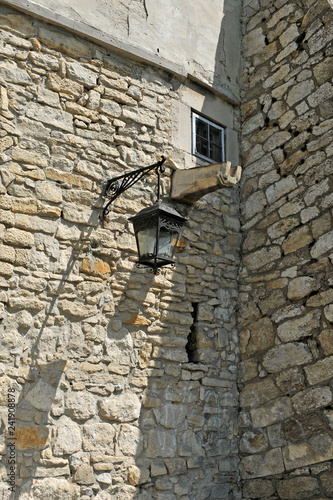 Fragment of the ancient castle with street lamp, window and water pipe for the rain.