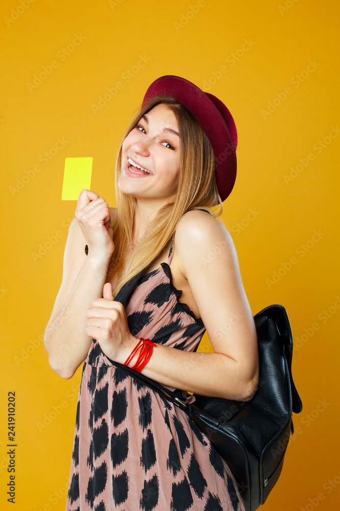 Happy tourist woman holding travel yellow case and credit card. Studio portrait. Vacation concept. Happy tourist woman holding travel yellow case and credit card. Studio portrait. Vacation concept.