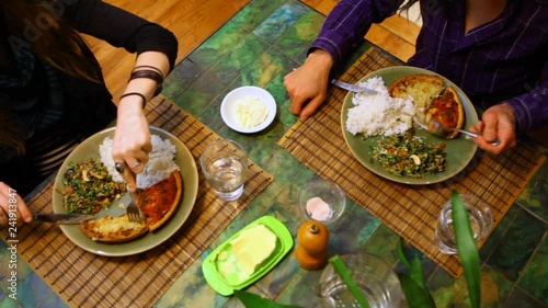 Couple having a meal together, sitting at a table and eating a quiche with salad and rice for diner - fixed angle, seen from above